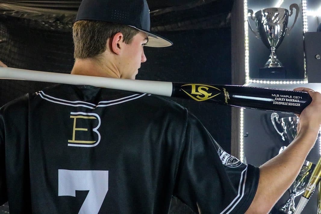 Player with bad over shoulders back to camera in front of large trophy case.